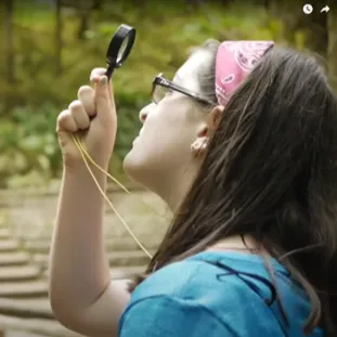 Girl looking at trees with a magnifying glass