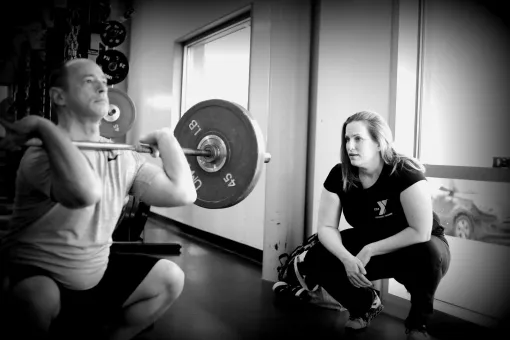 Personal trainer providing proper squat form coaching