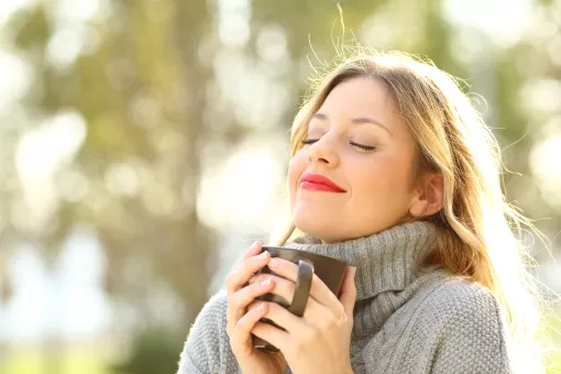 a person drinks coffee outdoors