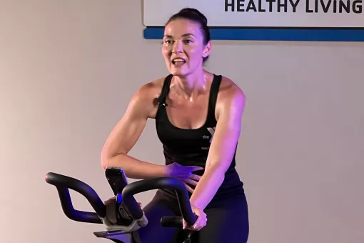 Instructor Jen Garrison sweats and speaks between sprints on a stationary cycling class on YMCA360