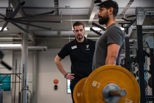 KickStart Coach Bryce watches member Benji lift weights to check for his form as part of the KickStart program. 