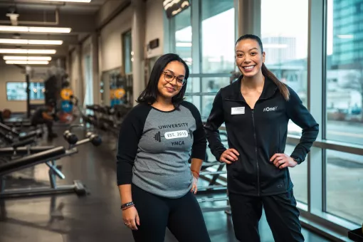 Wellness Coach Franchesca and a young woman member smile proudly at the camera.