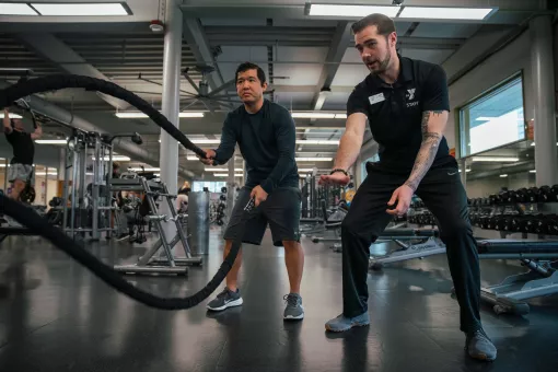 KickStart coach Bryce, provides technique support on the ropes at the University YMCA Student Center to a member.