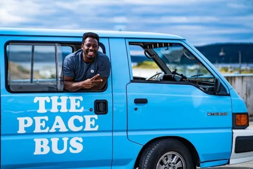 Kwabi throws up a peace sign from the window of his Peace Bus