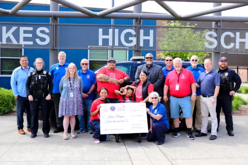 Lakewood community members smiling with a large check raised by the community and the Lakewood Police department at the YMCA