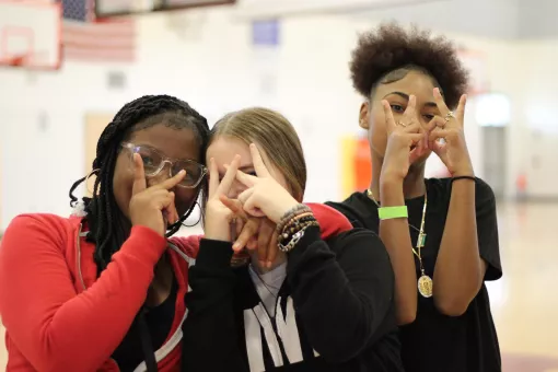A group of friends flash peace signs while hanging out at Teen Late Nite at the YMCA