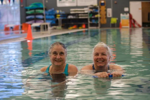 Two people smile in the pool at the YMCA
