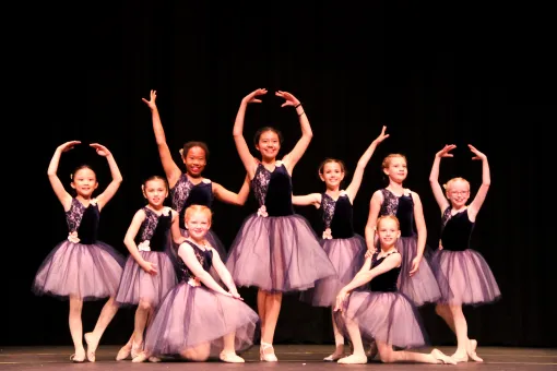 A group of girl ballet dancers on stage at a YMCA recital 