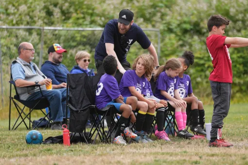 Youth Soccer coach boosts the morale of the benched players during a soccer game at the Gordon Family YMCA