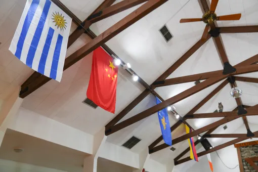 International flags hang from the wooden rafters inside the Lodge at Camp Seymour, showcasing the camp's welcoming community and global connections.