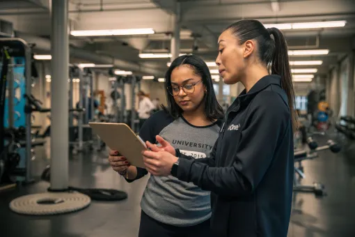 YMCA wellness coach reviews a personalized fitness plan with a member in a modern YMCA fitness center.