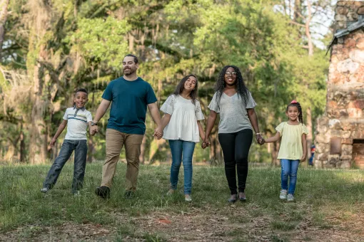 Family Holding Hands In The Park