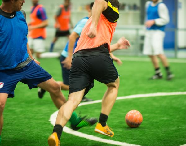 Two players battle it out for the ball during indoor soccer. 