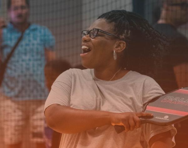 Pickleball player smiles with confidence after smashing a pickleball.