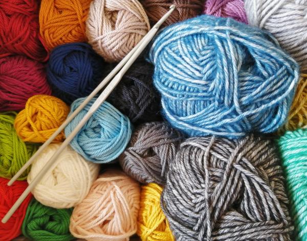 Balls of colorful yarn are viewed from above along with a set of knitting needles. 