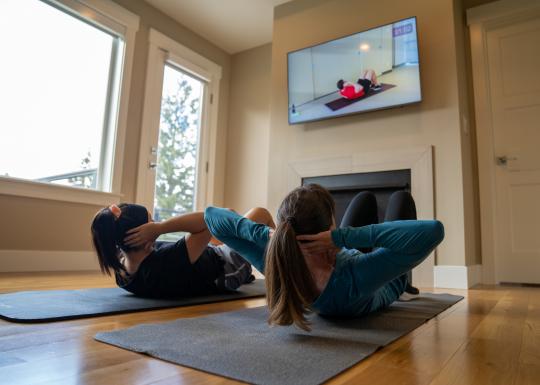 Mother and daughter doing sit ups together at home