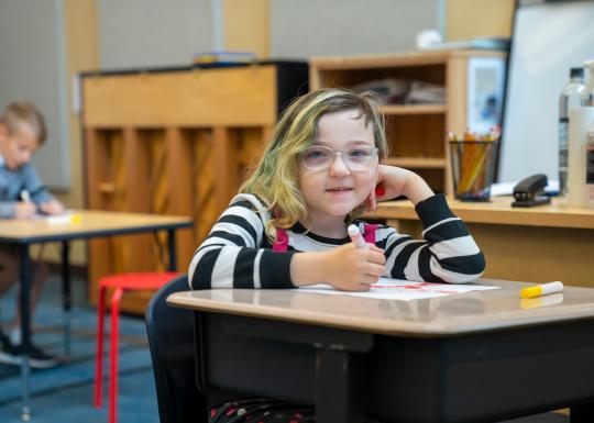 School Age Student Smiling At YMCA Child Care Desk