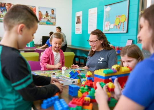 Childcare staff and youth playing board games and legos