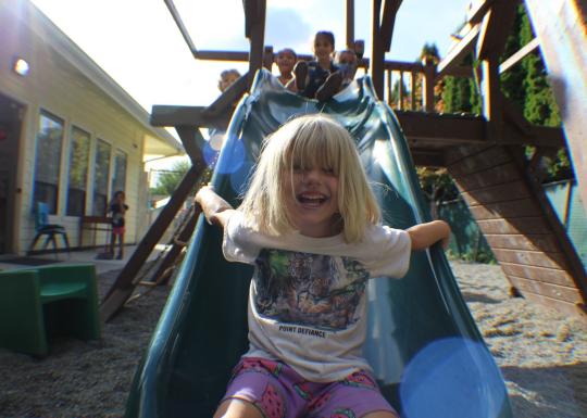 Kid smiling after riding slide at YMCA child care