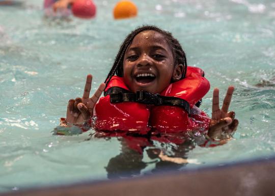Camper in life jacket showing a peace sign