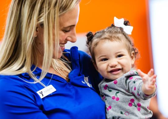 Infant Care staff holding smiling baby