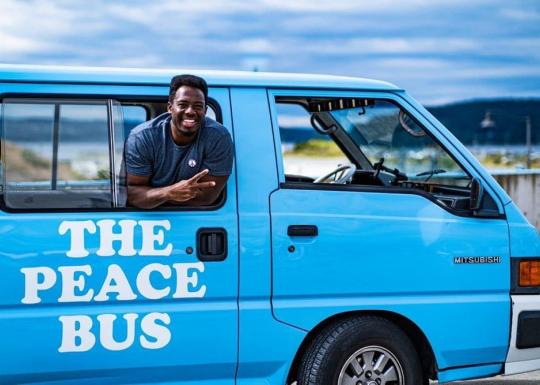 Kwabi throws up a peace sign from the window of his Peace Bus