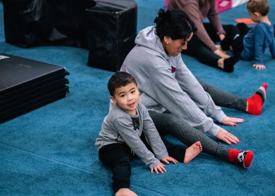 Toddler gym participant and parent stretch before a session