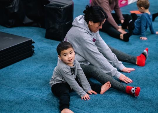 Toddler gym participant and parent stretch before a session