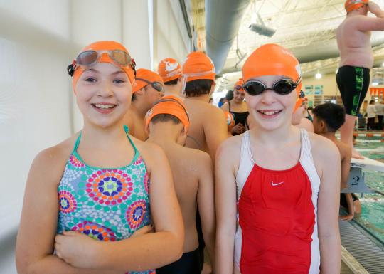 Swim team members pose for a photo poolside