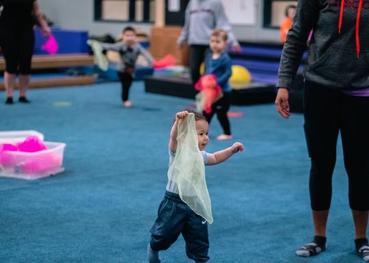 Toddler Gym participant holds up a juggling scarf during free tumble at the YMCA