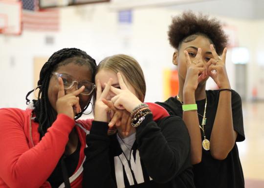 A group of friends flash peace signs while hanging out at Teen Late Nite at the YMCA