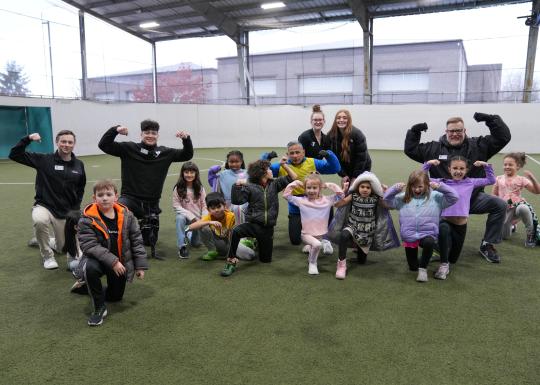 Summer camp participants flex for a photo on the astro turf at the YMCA