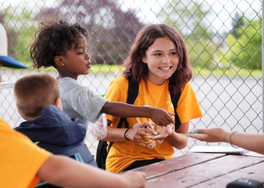 Summer camp students smile at the table while playing a game at the YMCA