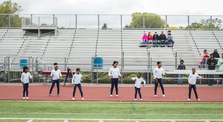 Youth Cheerleading participants practice a routine on the outdoor track at the YMCA