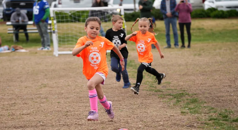 Action shot of a youth soccer player dribbling the ball toward the goal at the YMCA