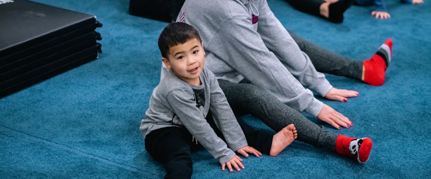 Toddler gym participant and parent stretch before a session