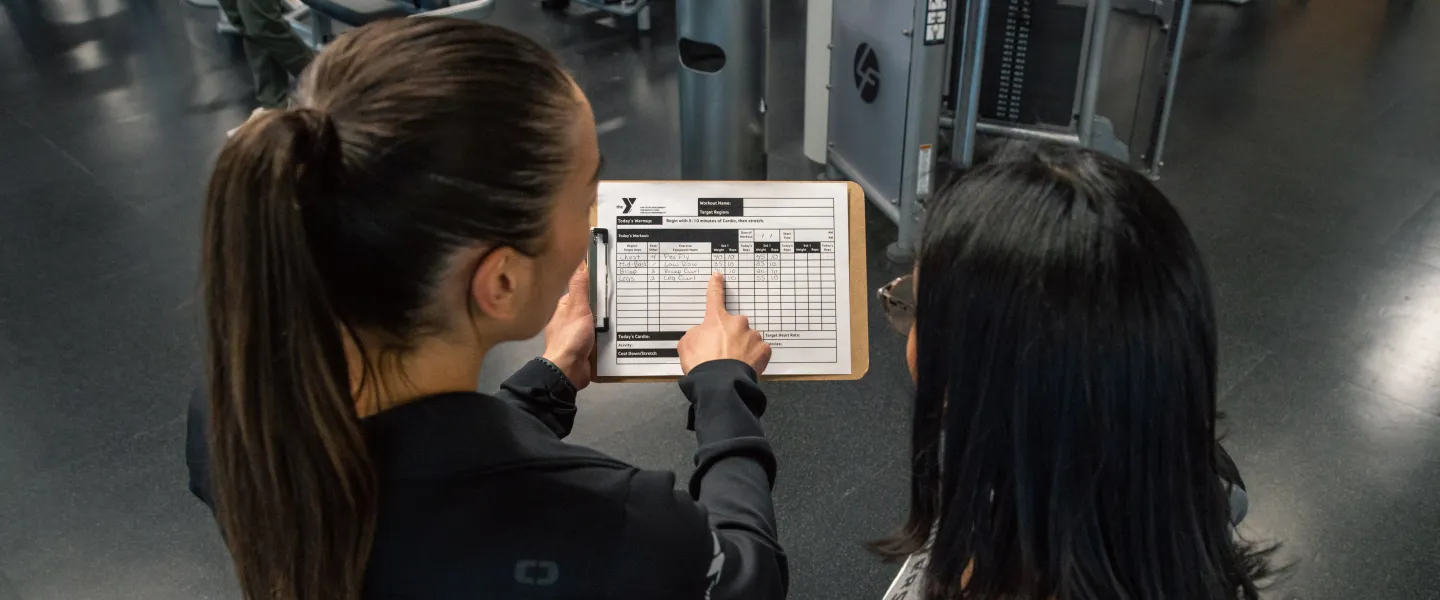 Staff goes over a workout plan with a member at the YMCA