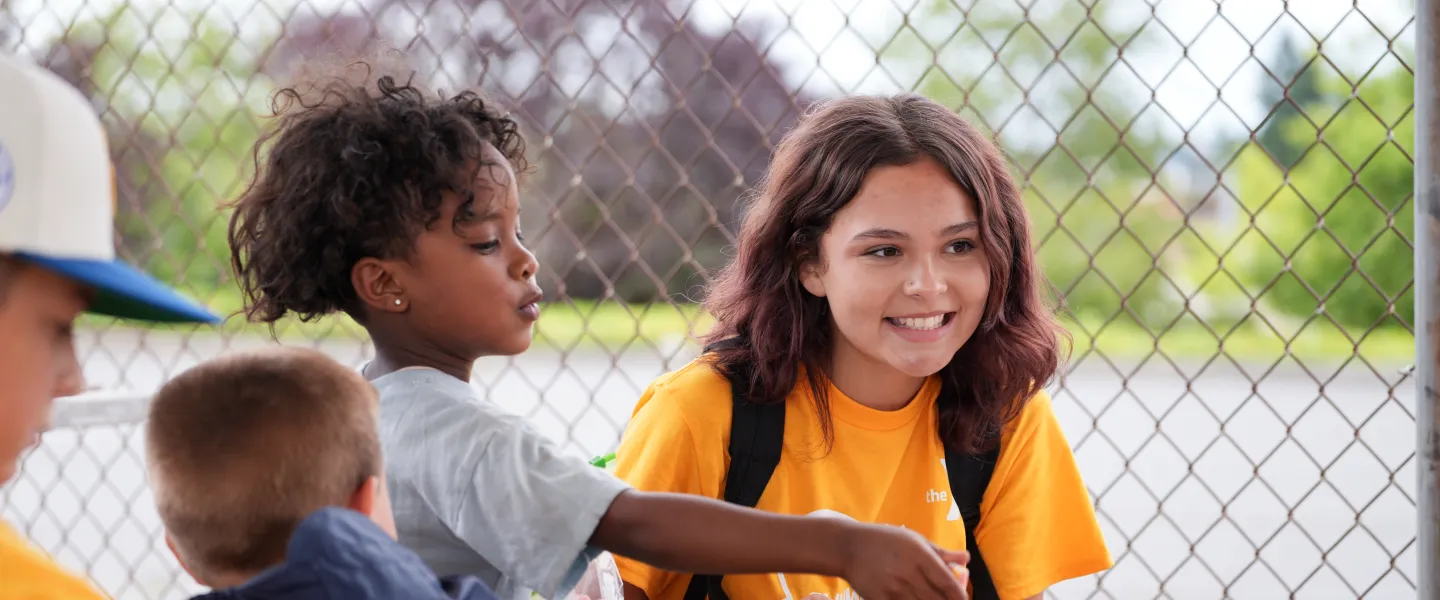 Summer camp students smile at the table while playing a game at the YMCA