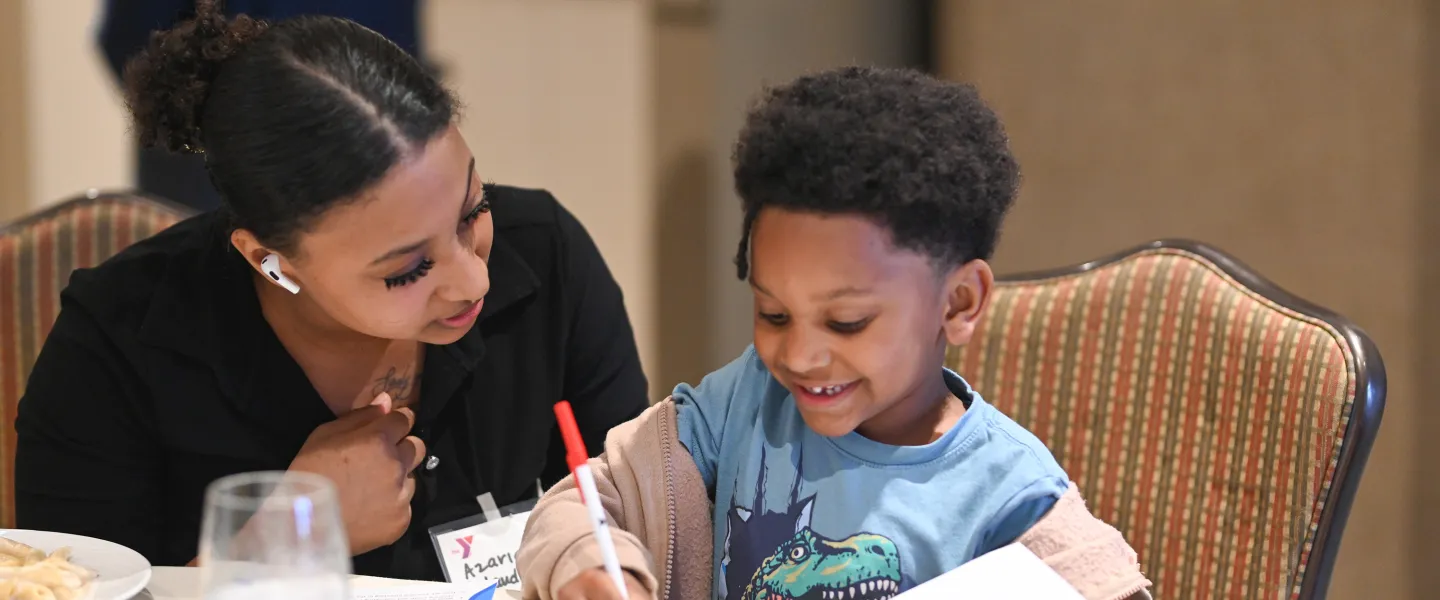 Staff Helping Young Student Draw