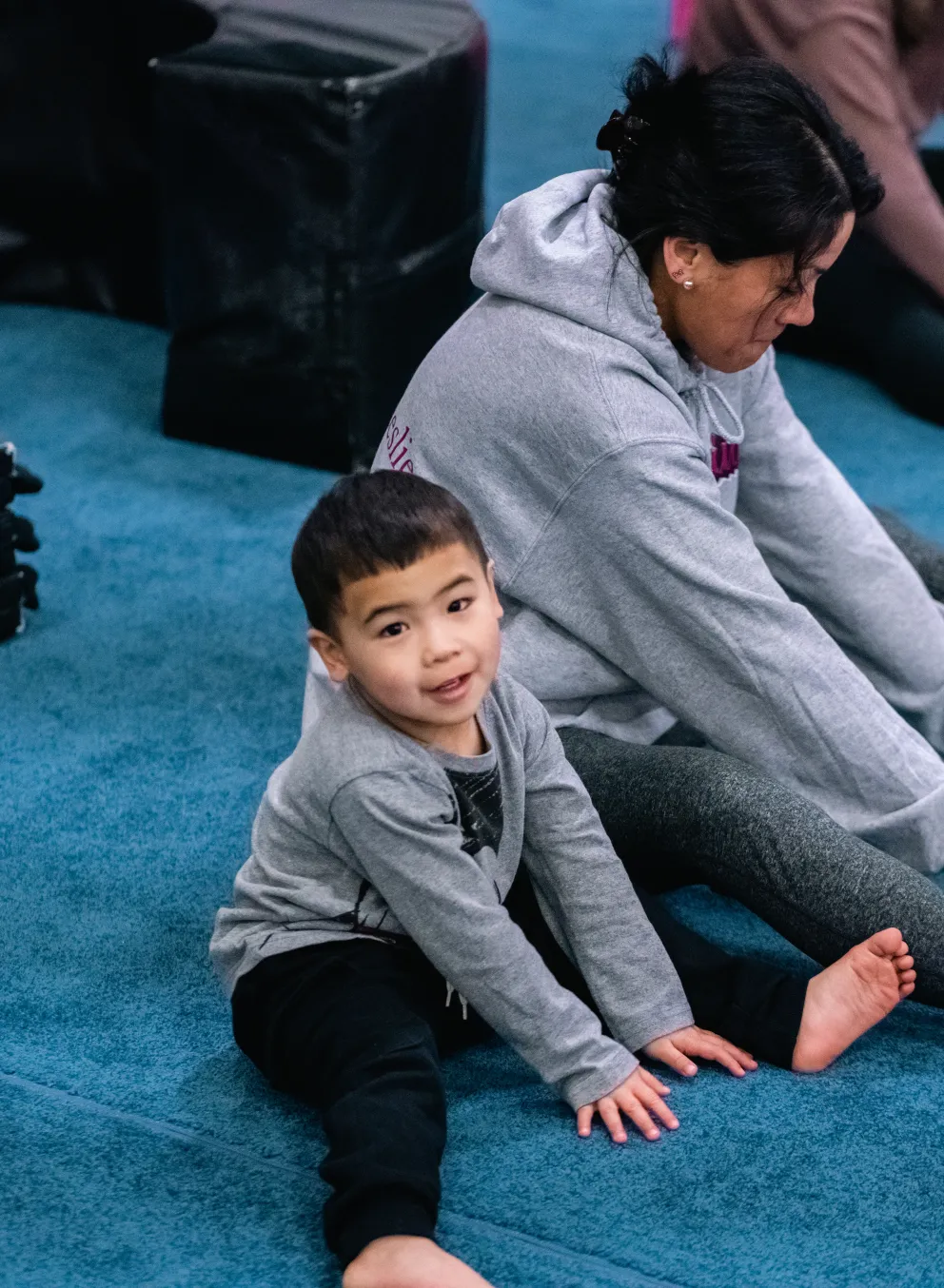 Toddler gym participant and parent stretch before a session