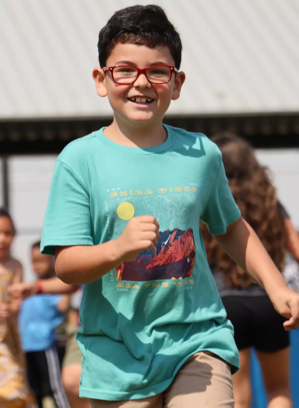 Campers run in the outdoor field at the YMCA during game time.