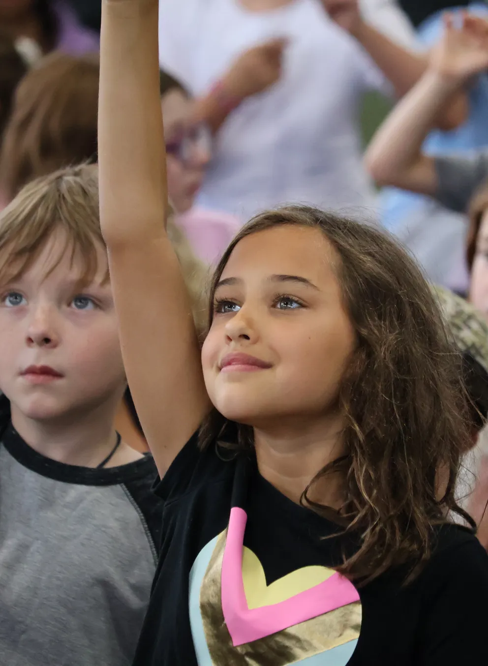 Campers raise their hands during an activity at the YMCA