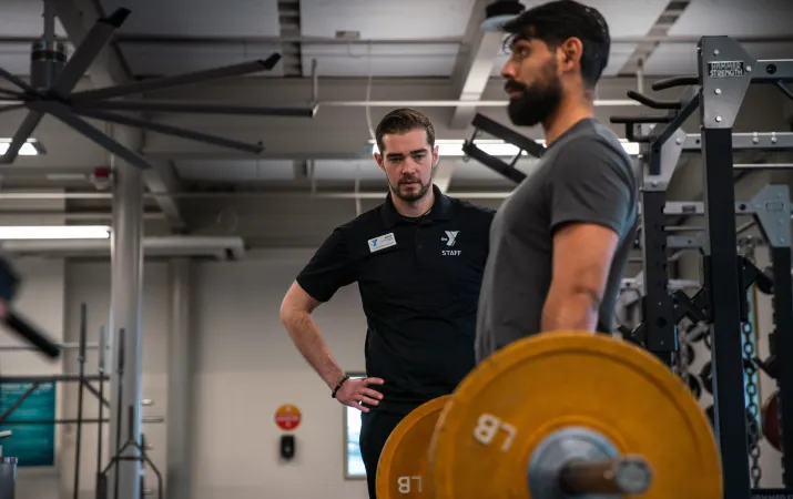 KickStart Coach Bryce watches member Benji lift weights to check for his form as part of the KickStart program.