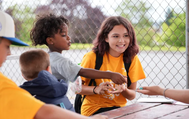 Summer camp students smile at the table while playing a game at the YMCA