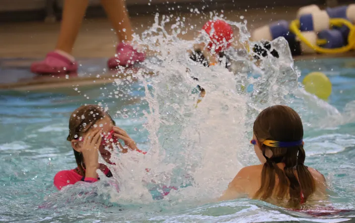 Summer day camp participants splash in the pool at the YMCA
