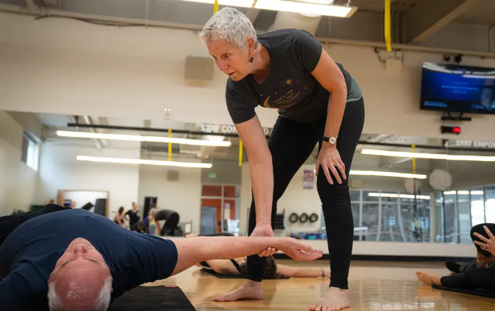 YMCA Group Exercise Instructor Helping Member Stretch