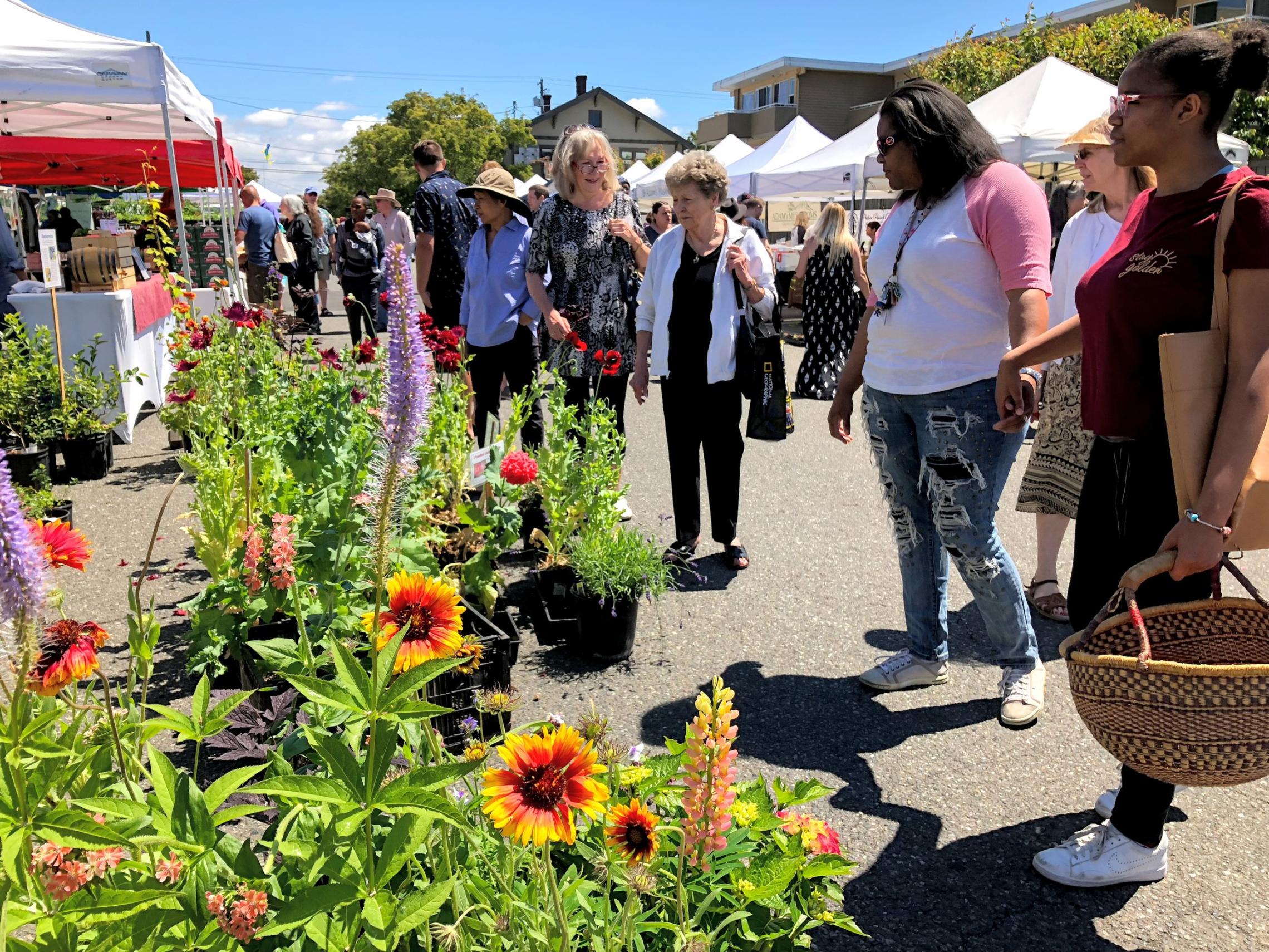 people walk next to fresh cut flowers at the tacoma farmers market in proctor.