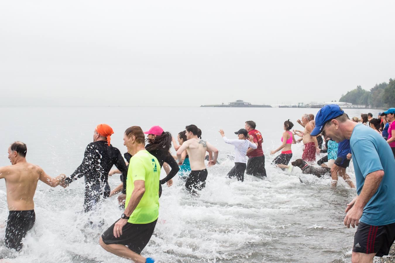People run into the Puget Sound at the Plunge hosted by the YMCA