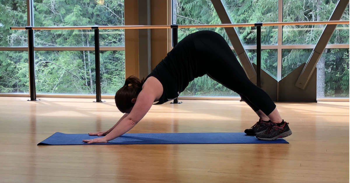 A person does yoga in front of a window.