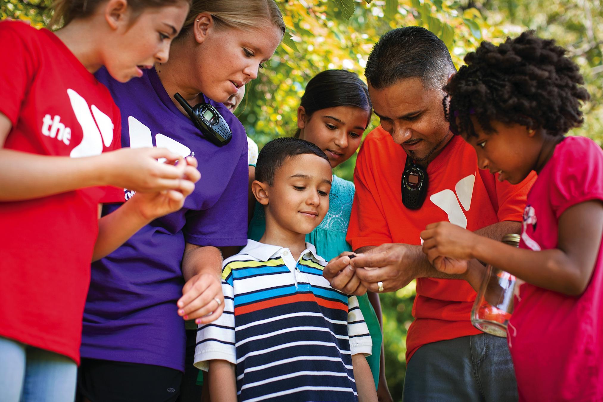 Children gather around a YMCA camp counselor.